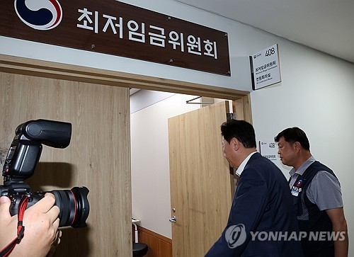 최저임금위원회 사용자위원인 류기정 한국경영자총협회 전무(왼쪽)와 근로자위원 류기섭 한국노총 사무총장이 10일 정부세종청사에서 열린 최저임금위원회 제12차 전원회의에서 민주노총 위원들이 심의를 거부한 채 퇴장해 회의가 정회된 후 밖에서 얘기를 나누고 들어오고 있다. [세종=연합뉴스]
