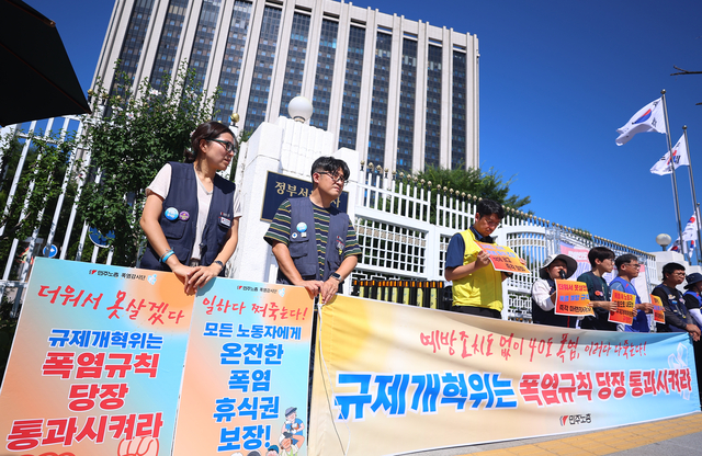 민주노총 조합원들이 지난 11일 서울 종로구 정부서울청사 앞에서 정부 규제개혁위원회(규개위)의 폭염 규칙 통과 촉구 기자회견을 하고 있다. 연합뉴스