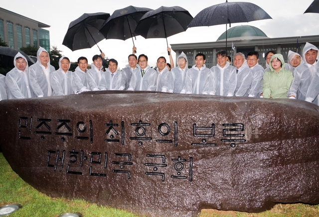 서울 여의도 국회 잔디광장에서 17일 열린 국회 상징석 제막식에서 우원식 국회의장, 더불어민주당 김병기 당대표 직무대행 겸 원내대표 등 참석자들이 기념촬영을 하고 있다. 상징석에는 국회가 민주주의의 보루로서 ‘12·3 비상계엄’ 해제를 이끌었다는 내용의 문구가 새겨져 있다. 국회사진기자단=연합뉴스.