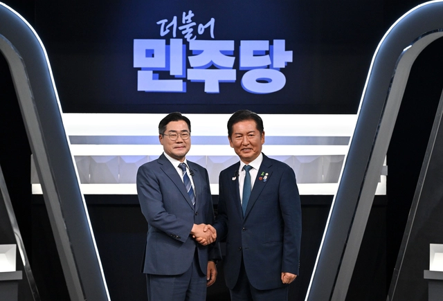 더불어민주당 8·2 전당대회 당대표 후보인 박찬대·정청래 의원이 지난 7월27일 서울 여의도 KBS 신관 공개홀에서 열린 당대표 후보자 TV토론회 시작에 앞서 악수를 하며 기념촬영하고 있다.<국회사진기자단·연합뉴스>