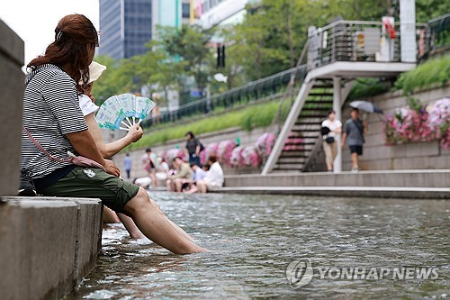 폭염이 이어진 1일 서울 청계천을 찾은 한 시민이 발을 물에 담그고 부채질하고 있다. [연합뉴스]