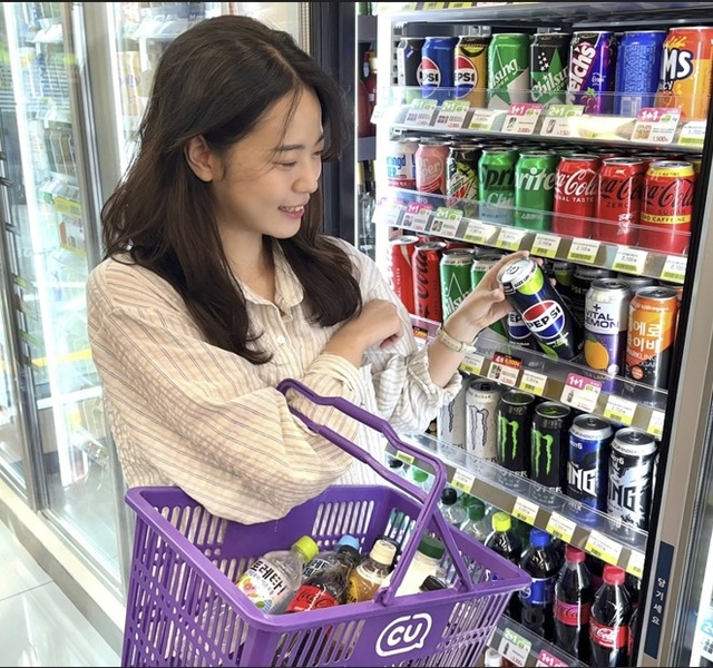 CU 매장에서 모델이 음료 제품을 고르고 있다. [CU 제공]