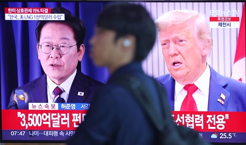 한국과 미국의 관세협상이 타결된 31일 서울역 대합실에서 한 시민이 관련 뉴스가 나오는 TV 앞을 지나고 있다.   [연합뉴스]