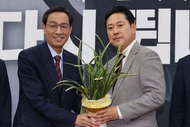 우상호(왼쪽) 대통령실 정무수석이 27일 국회 본청을 찾아 장동혁(오른쪽) 국민의힘 신임 당대표를 예방해 이재명 대통령이 보낸 축하난을 전달하고 있다.<연합뉴스 사진>
