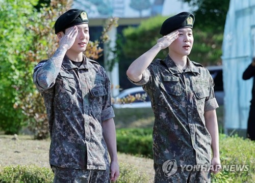 육군 병장으로 만기 전역한 BTS 지민과 정국이 11일 경기 연천군 연천공설운동장에서 열린 기념행사에서 팬들에게 거수경례로 전역 인사하고 있다.   [연합뉴스]