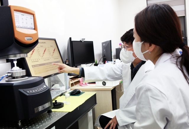 코스맥스 연구원과 박준동(뒷쪽) 숙명여대 화공생명공학부 교수가 박 교수의 연구실에서 인공지능(AI)으로 분석한 에센스 제형 연구 자료를 살펴보고 있다. [코스맥스 제공]