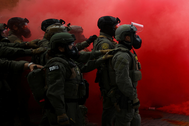 무장한 연방요원들이 4일(현지시간) 미국 오리건주 포틀랜드의 이민세관단속국(ICE) 본부 앞에서 벌어진 시위를 진압하기 위해 연막을 피우고 서 있다. [로이터=연합뉴스]