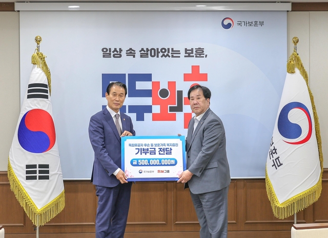 우오현(오른쪽) SM그룹 회장과 권오을 국가보훈부 장관이 13일 정부세종청사에서 열린 전 국민 보훈 기부 프로젝트 ‘모두의 보훈 드림’ 후원금 전달식에서 기념촬영을 하고 있다. SM그룹 제공.