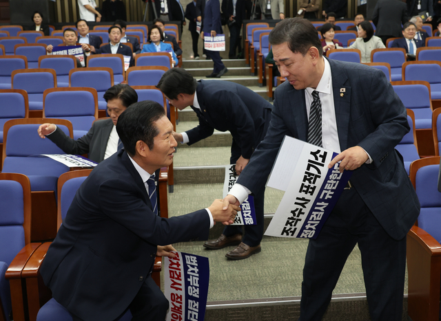 정청래 더불어민주당 대표와 김병기 원내대표가 13일 서울 여의도 국회에서 열린 의원총회에서 악수하고 있다. [연합뉴스]