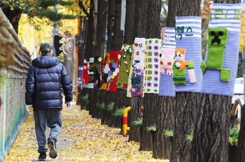 북쪽에서 찬 공기가 유입되며 추위가 찾아온 17일 경기도 광명시의 한 거리에서 두꺼운 옷차림의 시민들이 뜨개옷 입은 가로수길을 걷고 있다. [광명=연합뉴스]