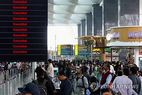 인도 남부 벵갈루루 공항에서 6일(현지시간) 인디고 항공의 운항이 줄줄이 취소됐다는 전광판 표시를 승객들이 바라보고 있다. [벵갈루루(인도) 로이터=연합뉴스]