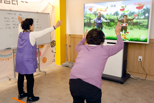 화면에 나오는 자신의 모습을 보며 게임을 즐기는 어르신들