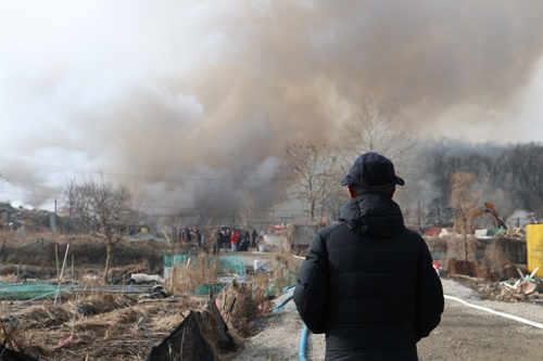 16일 서울 강남구 개포동 구룡마을 4지구 화재현장 소방 통제선 밖에서 주민이 현장을 지켜보고 있다. [연합뉴스]