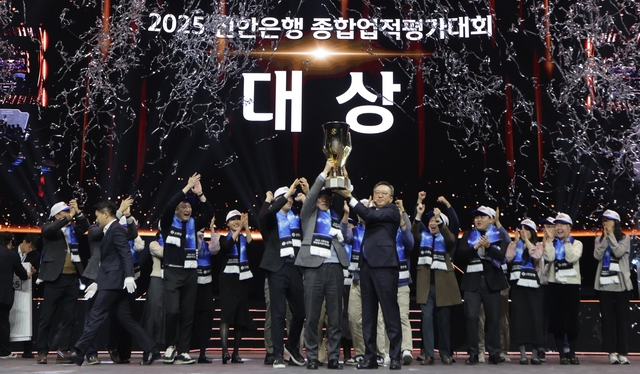 정상혁(가운데 오른쪽) 신한은행장과 박현종(가운데 왼쪽) 센터장이 지난 17일 인천광역시 중구 인스파이어 엔터테인먼트 리조트 아레나에서 열린 ‘2025년 종합업적평가대회’에서 챔피언 트로피를 들어올리고 있다. [신한은행 제공]