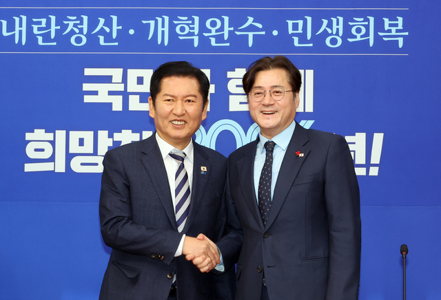 더불어민주당 정청래 대표가 21일 국회에서 취임 인사차 방문한 홍익표 청와대 정무수석을 만나 악수하고 있다. [연합뉴스]