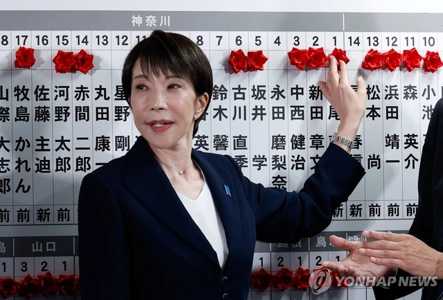 다카이치 사나에 일본 총리가 지난 2월 8일 중의원 선거(총선)에서 승리한 집권 자민당 후보 이름 위에 꽃을 붙이고 있다.[로이터 연합뉴스]