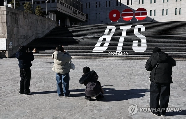 22일 서울 종로구 세종문화회관 계단에서 외국인 관광객들이 오는 3월 3년 9개월 만에 ‘완전체’로 돌아오는 그룹 방탄소년단(BTS)의 컴백을 알리는 홍보물을 기념촬영하고 있다. [연합뉴스]
