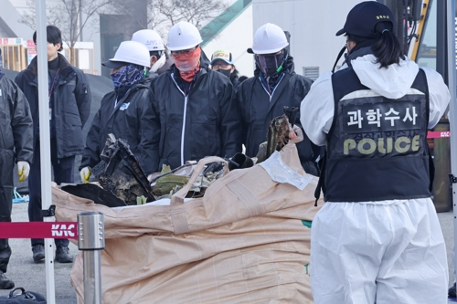 12일 무안국제공항에서 공항 관계자들이 12·29 제주항공 여객기 참사 사고기 잔해를 옮기고 있다. [무안=연합뉴스]
