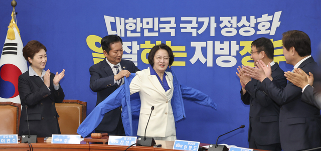정청래 더불어민주당 대표가 13일 국회에서 최고위원회의에 앞서 열린 추미애 경기도 지사 후보 환영식에서 추 후보에게 선거용 점퍼를 입혀주고 있다. [연합뉴스]