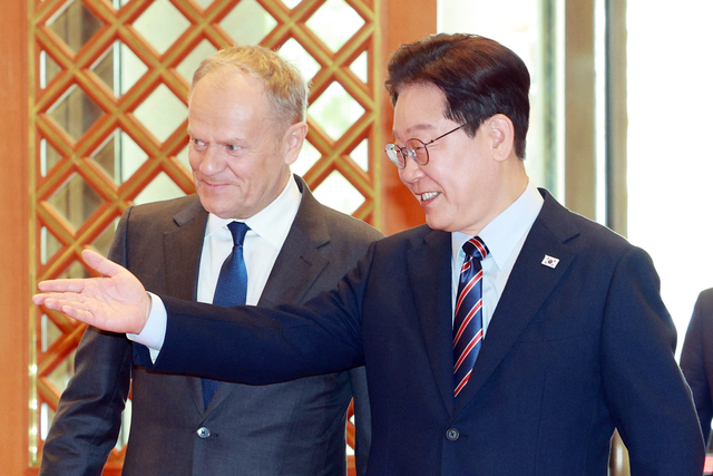이재명 대통령이 13일 청와대에서 공식 방한한 도날트 투스크 폴란드 총리와 방명록 서명식장으로 이동하고 있다. [연합뉴스]