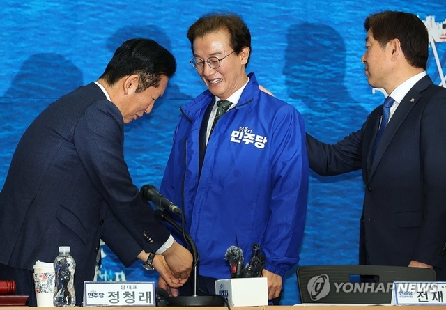 더불어민주당 정청래 대표가 15일 오전 부산 동구 부산항국제전시컨벤션센터에서 열린 부산 현장 최고위원회에서 전재수 부산시장 후보에게 파란 점퍼를 입혀주고 있다. 연합뉴스
