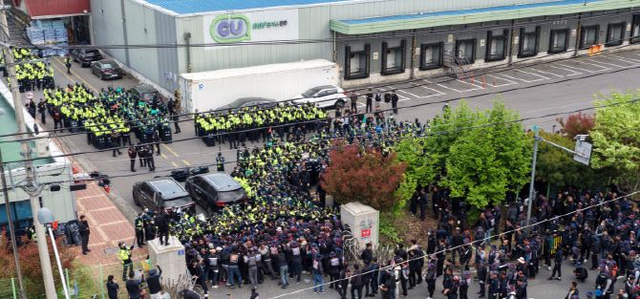 지난 20일 오후 경남 진주시 정촌면BGF로지스 진주센터에서 화물연대 관계자가 센터 입구로 진입하려는 과정에서 경찰과 대치하고 있다. [연합뉴스]
