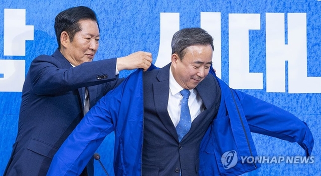 6·3 재보선에서 더불어민주당 후보로 광주광역시 광산을 선거구에 공천이 유력한 임문영 AI전략위원회 상근부위원장(오른쪽)이 6일 국회에서 열린 더불어민주당 인재 영입식에서 정청래 대표에게 민주당 상징인 ‘파란 점퍼’를 전달받은 뒤 입고 있다.  연합뉴스