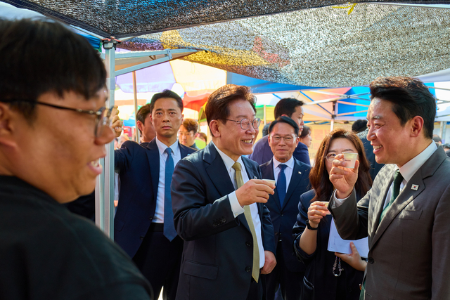 이재명 대통령이 14일 성남 모란시장에서 강훈식 비서실장과 시식을 하며 대화하고 있다.  연합뉴스
