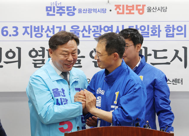 김상욱 더불어민주당 울산시장 후보와 김종훈 진보당 후보가 15일 울산시의회 프레스센터에서 6·3 지방선거 울산시장 후보 단일화 합의를 발표한 후 손을 맞잡고 있다. [연합뉴스]
