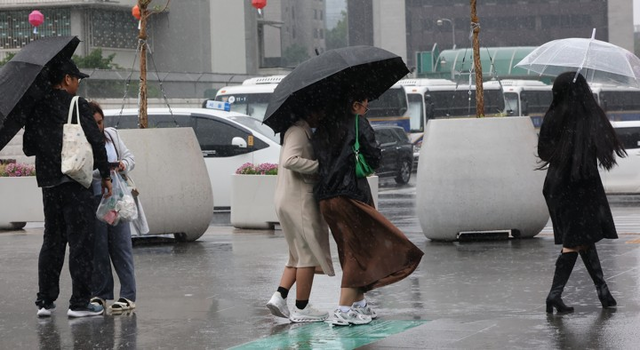지난 20일 서울 광화문광장 부근에서 외국인 관광객들이 비바람을 맞으며이동하고 있다. [연합뉴스]