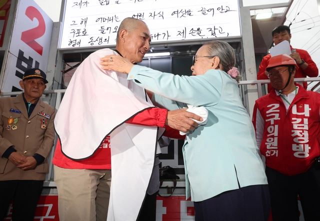 박민식 국민의힘 부산 북갑 보궐선거 후보가 21일 부산 구포시장 쌈지공원에서 열린 출정식에서 어머니의 도움으로 삭발한 뒤 어머니와 포옹하고 있다. 박 후보는 삭발하며 “배신자 한동훈과 단일화하지 않겠다”고 말했다. [연합뉴스]