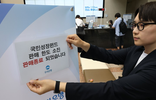 국민참여성장펀드 가입 첫날인 22일 서울 중구 우리은행 본점 영업점에서 한 직원이 한도소진으로 인한 판매종료 안내문을 붙이고 있다. [연합뉴스]