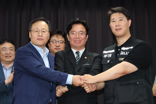 지난 20일 경기 수원시 경기고용노동청에서 열린 삼성전자 임금협상을 마친 후 여명구 삼성전자 DS(디바이스솔루션·반도체 사업 담당) 피플팀장과 최승호(오른쪽) 삼성그룹 초기업노동조합 삼성전자지부 위원장이 잠정 합의안에 서명한 후 김영훈(가운데) 고용노동부 장관과 손을 맞잡고 있다.  [사진공동취재단]