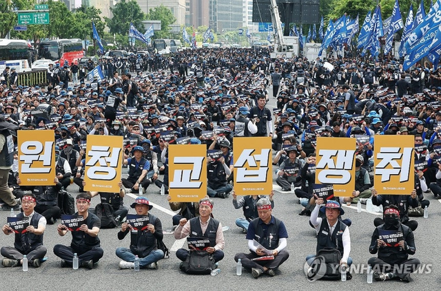 전국금속노동조합(금속노조) 조합원들이 10일 서울 종로구 광화문광장 인근에서 열린 결의대회에서 손팻말을 들고 있다.  연합뉴스