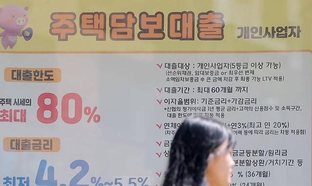 서울 시내 한 은행 점포에 걸려있는 주택담보대출 상품 현수막 앞을 한 시민이 걸어가고 있다. 연합뉴스
