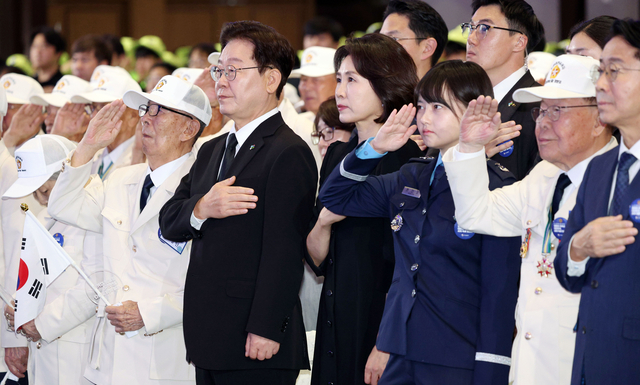 이재명 대통령과 김혜경 여사가 25일 수원컨벤션센터에서 열린 6·25전쟁 제76주년 기념식에서 국기에 경례하고 있다. 연합뉴스
