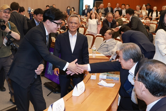 한동훈(왼쪽) 무소속 의원이 지난 6월 29일 국회박물관에서 열린 김덕룡 김영삼민주센터 이사장 회고록 출판기념회에 참석하며 김무성(오른쪽) 국민의힘 전 의원과 악수를 나누고 있다. 한동훈 의원은 국민의힘 당대표, 김무성 전 의원은 국민의힘 전신인 새누리당 시절 대표최고위원을 지냈다. [연합뉴스]