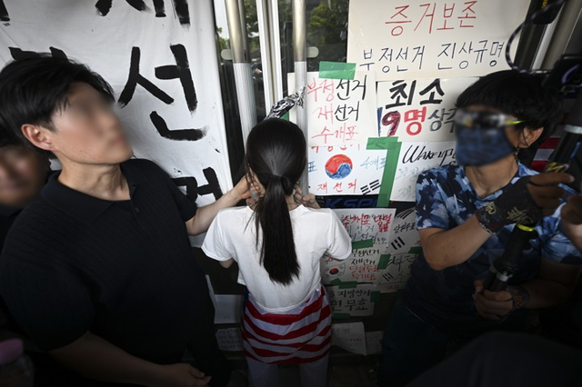 ‘6·3 지방선거’ 투표용지 부족 사태로 촉발된 서울 송파구 올림픽공원 핸드볼경기장 일대 ‘개표소 봉쇄 시위’가 이어지던 지난 6월 16일 한 시위 참가자 여성이 단신으로 대한체육회 등 입주 단체 관계자들의 사무실 진입을 막아서고 있다. 해당 여성은 집회 참여자나 네티즌 사이에서 ‘올다르크’(올림픽공원 + 잔다르크)로 불리고 있다. [사진공동취재단·연합뉴스]