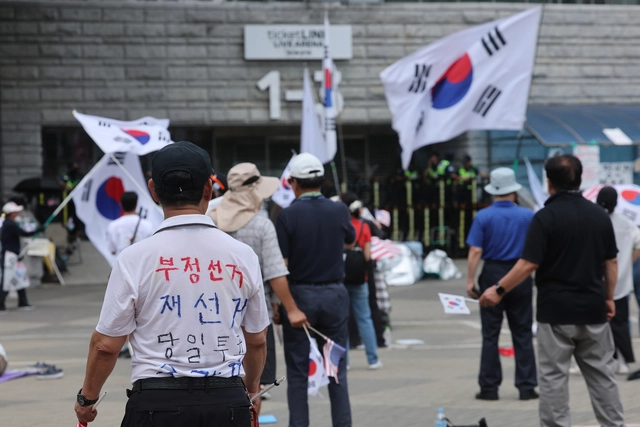 6·3 지방선거 투표용지 부족 사태로 인한 ‘개표소 봉쇄 시위’가 한달째 계속된 지난 7월 5일 서울 송파구 올림픽공원 핸드볼경기장 출입문 앞에서 참가자들이 구호를 외치고 있다. [연합뉴스]