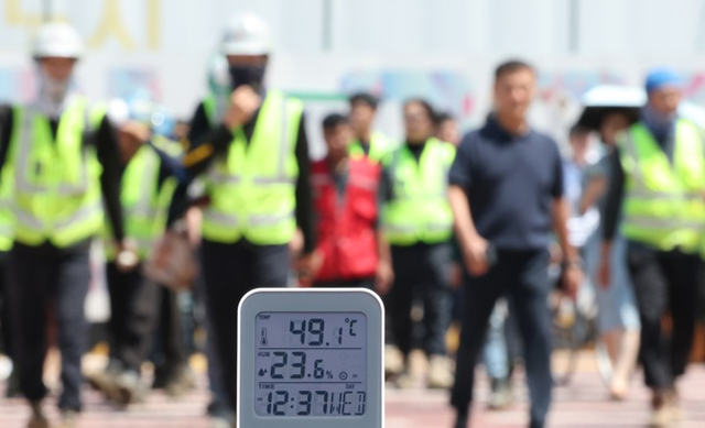 서울 전역에 ‘폭염중대경보’가 발효된 5일 서울 강남구 한 공사현장 부근 횡단보도에서 공사 관계자들이 이동하고 있다. [연합뉴스]