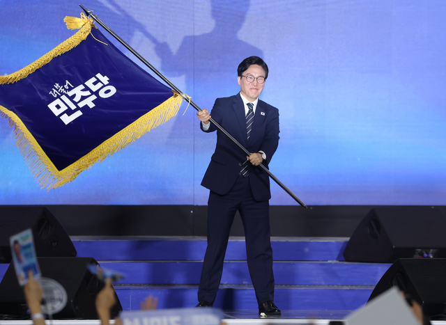 더불어민주당 당 대표에 출마한 김민석 전 총리가 17일 대전 컨벤션센터에서 열린 제3회 더불어민주당 정기 전국당원대회에서 당 대표 당선을 확정한 뒤 당기를 흔들고 있다.   [연합뉴스]