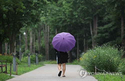 갑자기 소나기가 내린 지난 14일 서울 마포구 경의선숲길공원에서 한 시민이 우산을 쓰고 이동하고 있다. [연합뉴스]
