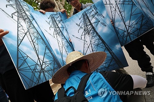 고압송전선로·철탑건설반대영암군대책위원회가 지난 7월 7일 서울 종로구 청와대 앞에서 연 신해남-신장성 345kV 송전선로 철회 촉구 결의대회에서 참가자들이 송전탑 손팻말을 들고 퍼포먼스를 하고 있다. [연합뉴스 자료사진]