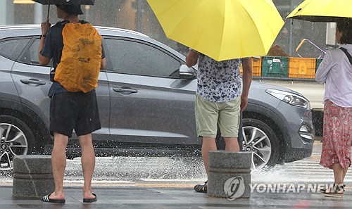 전국 대부분 지역에 비가 내린 지난 8월 28일 부산 해운대해수욕장 인근 횡단보도에서 관광객들이 우산을 쓰고 신호를 기다리는 동안 지나가는 차량이 도로에 고인 빗물을 튀기고 있다. [부산=연합뉴스]